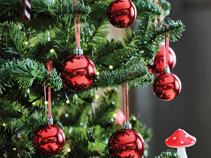 Christmas tree decorated with shiny red ornaments and warm lights.