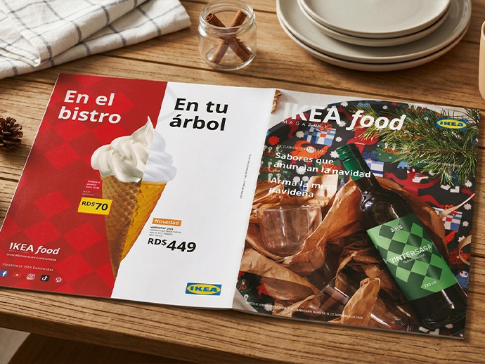 Front cover of "IKEA food MAGAZINE" placed on a terracotta-colored table next to a plate with a meal, cutlery, and a glass of pink drink.