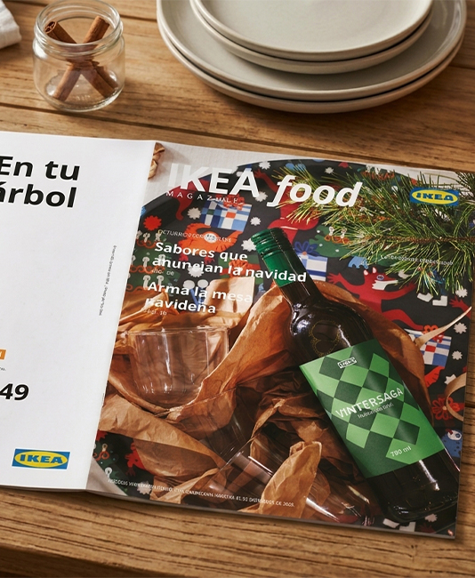 Close-up of the "IKEA food magazine" cover on a terracotta table, featuring snacks like potato chips, chocolate bars, and mixed nuts.