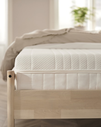 Colchón blanco sobre cama de madera clara.